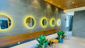 A modern reception area with a wooden ceiling, circular wall lights, a bench, and potted plants. - Duke Casa Apartment (Da Nang Municipality)
