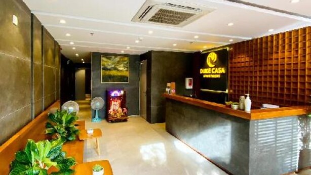 A hotel reception area with a reception desk, seating area, and a wall-mounted air conditioning unit. - Duke Casa Apartment (Da Nang Municipality)