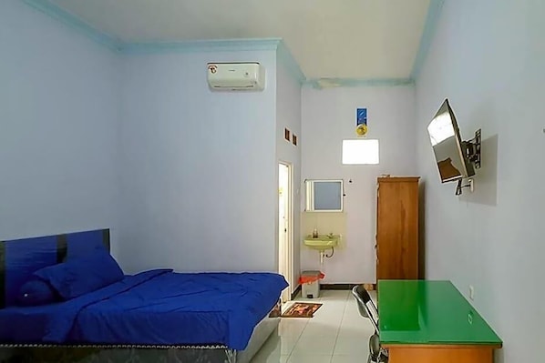 Un dormitorio con cama, espejo, lavamanos y un armario verde.