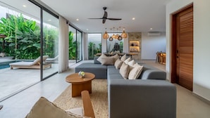 Ein modernes Wohnzimmer mit Sofa, Couchtisch und einem Essbereich mit Tisch und Stühlen.