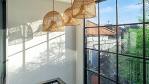 Ein Zimmer mit großen Fenstern, einer Treppe und drei Korbstühlen-Pendelleuchten.