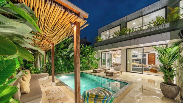 Ein modernes Haus mit Swimmingpool, überdachter Terrasse und üppiger Bepflanzung.