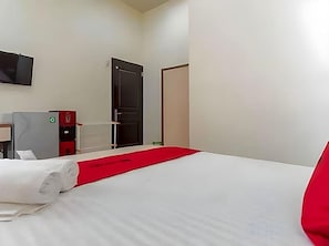 Une chambre d’hôtel avec un lit, un bureau, une chaise, une télévision et une porte.
