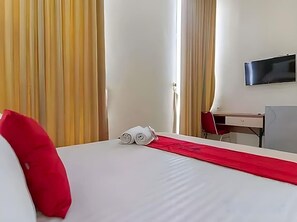 Une chambre d’hôtel avec un lit, un bureau, une chaise, une télévision et des rideaux.