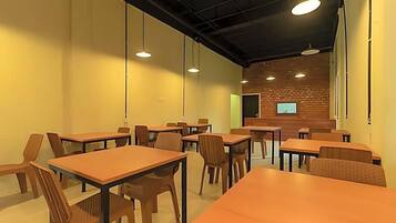 A conference room with tables and chairs, a brick wall, and a projector screen.