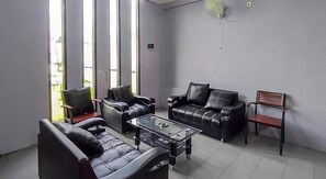 A modern living room with leather sofas, a glass coffee table, and large windows. - Wisma Tulus Syariah Kebumen Redpartner (Kebumen)