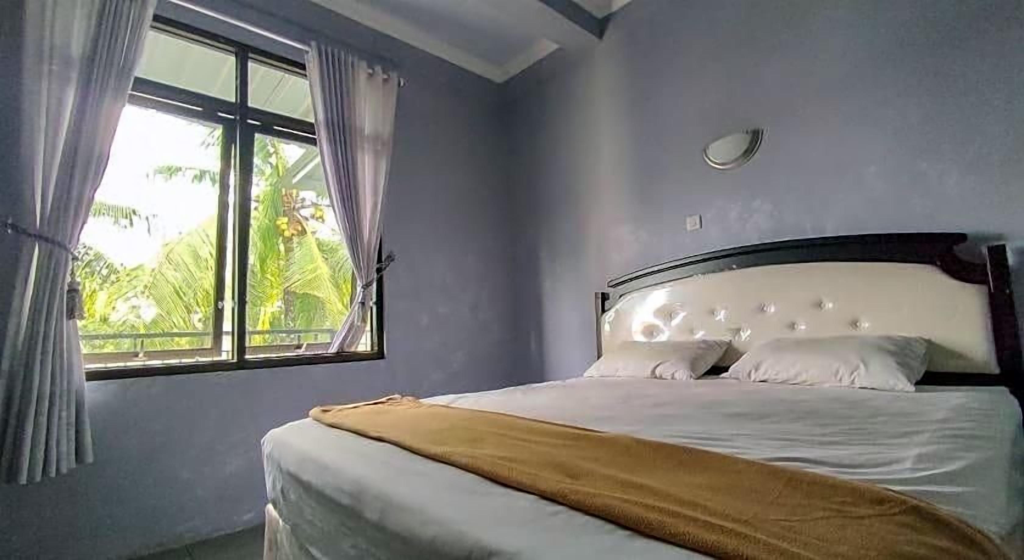 A bedroom with a bed, a window, and curtains.