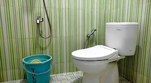 A bathroom with a toilet, a shower, and a blue bucket.