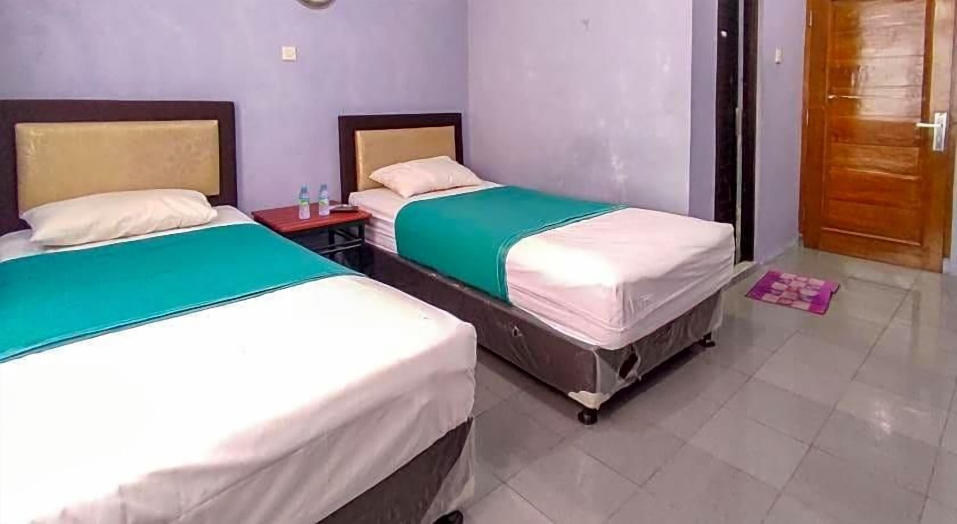 A hotel room with two beds, a nightstand, and a door.