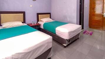 A hotel room with two beds, a nightstand, and a door.