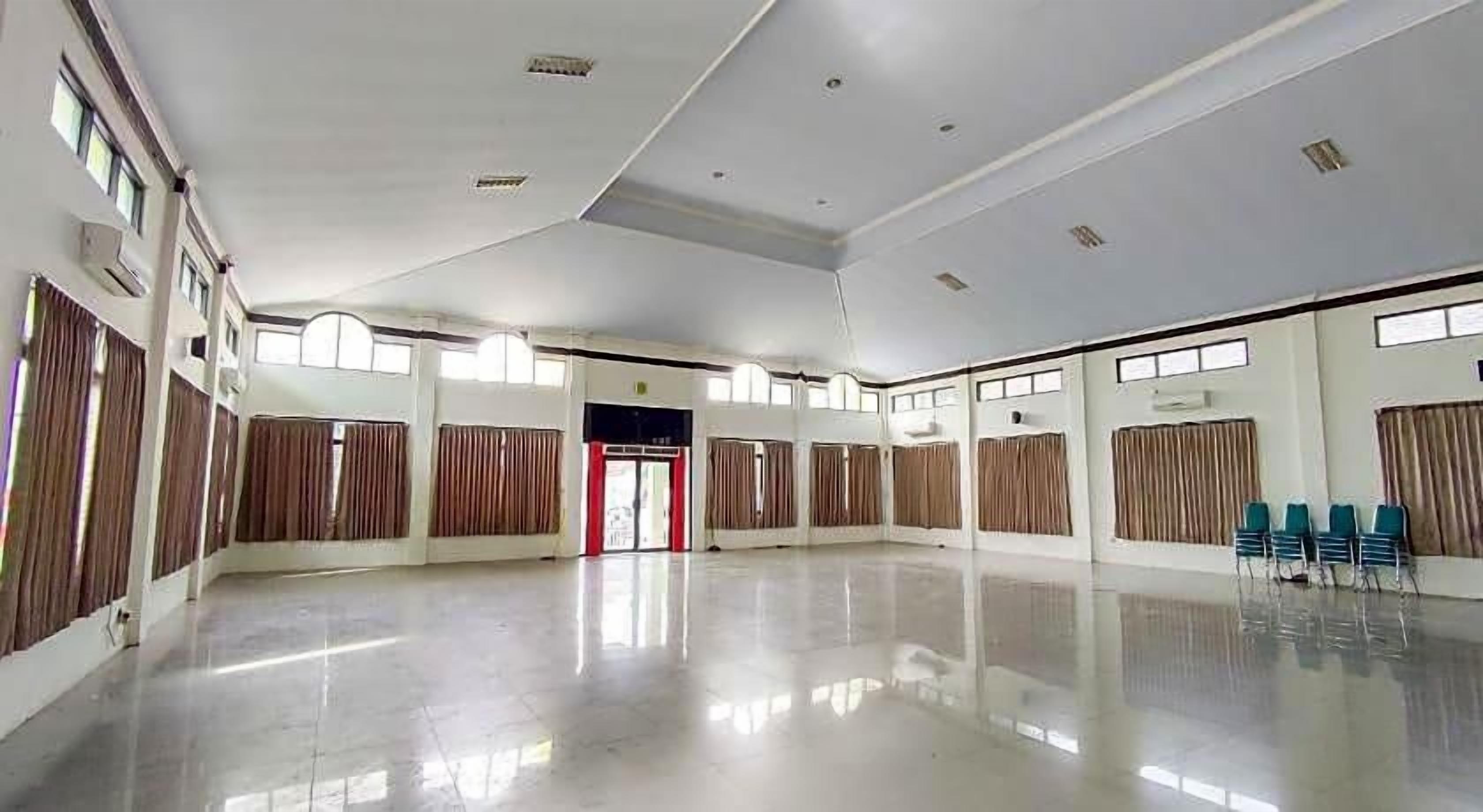 A spacious hall with a high ceiling, large windows, and a reflective floor.
