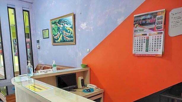 A reception desk with a glass top, a calendar, and a framed picture on the wall.
