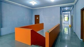 A hotel room with a long corridor, a reception desk, and a door.