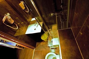 A modern bathroom with a glass shower enclosure, a white toilet, and a sink with a mirror. - Plug Inn Montmartre By Hiphophostels (Paris)