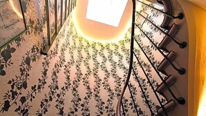 Un escalier orné d’un papier peint à motifs floraux et doté d’une rampe en métal.