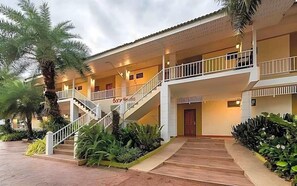 Un hotel con estructura de dos pisos, una escalera central y un área exterior cubierta con plantas.