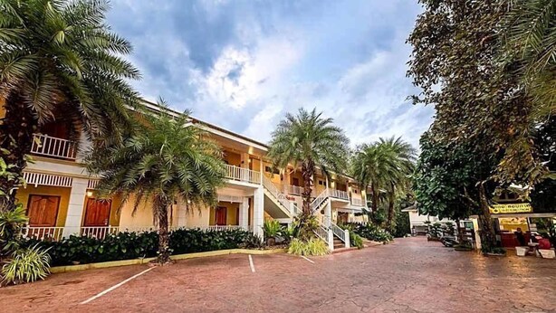 Un hotel con patio, palmeras y un paseo techado.