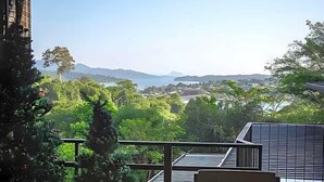 Un balcón con vistas a un paisaje costero, que incluye árboles y montañas lejanas.