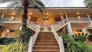 A hotel with a central staircase, a covered entrance, and a sign with text.