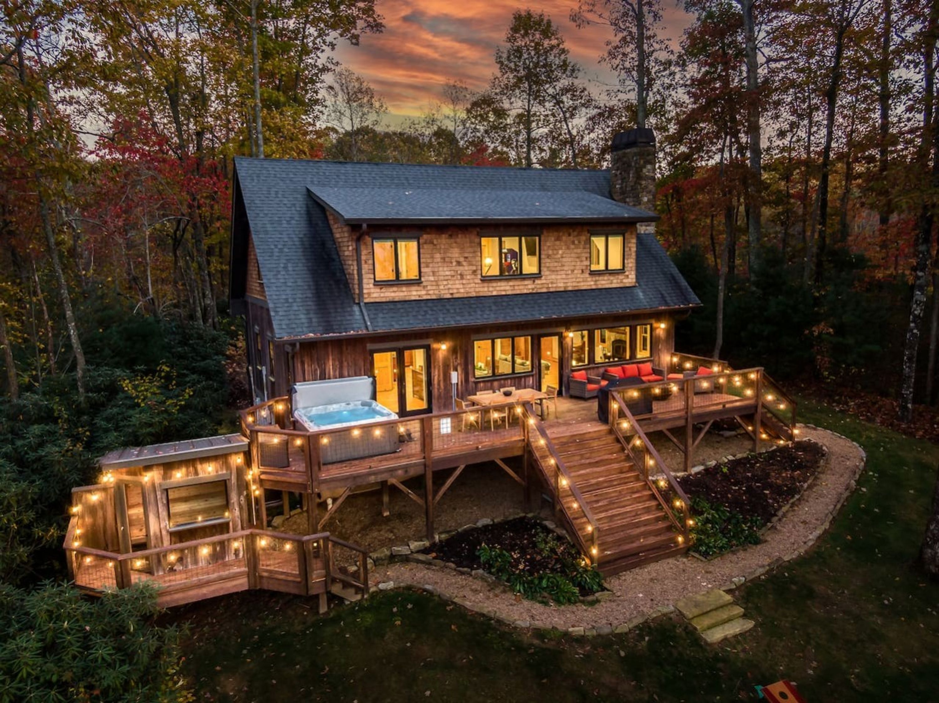 Une cabane en bois à deux étages, dotée d’un bain à remous, d’une terrasse et d’un espace salon extérieur.