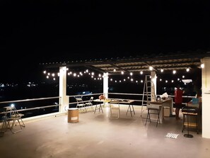 An outdoor patio with string lights, chairs, tables, and a ladder. - Lhong Lay House (Sattahip)