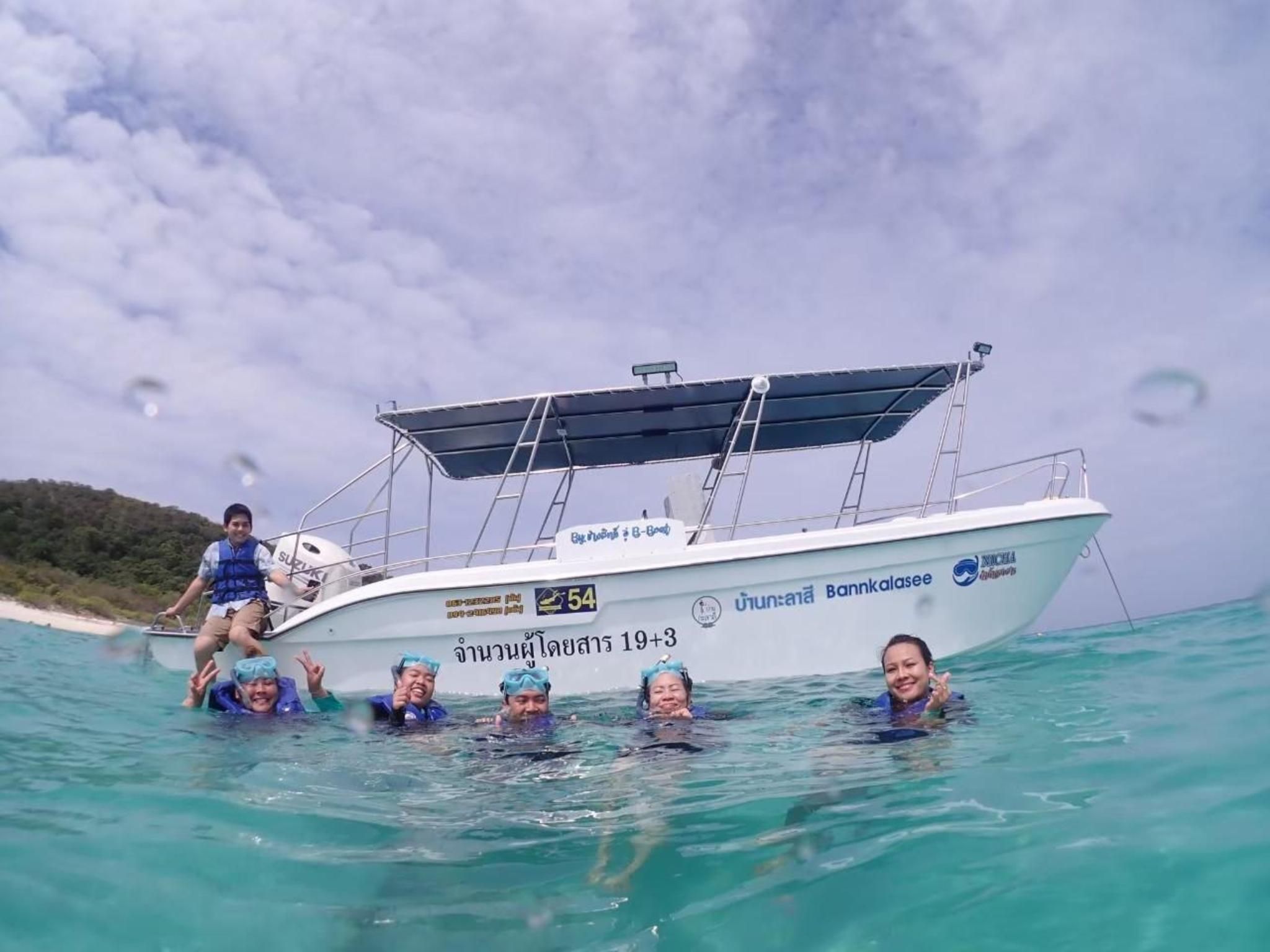 A boat with people in the water, a clear sky, and a beach in the background.