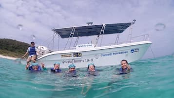 A boat with people in the water, a clear sky, and a beach in the background.