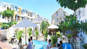 A poolside area with outdoor seating and umbrellas, surrounded by buildings. - Hung Vuong Hotel (Tuy Hoa)