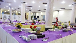 A banquet hall with tables covered in purple tablecloths, white chairs, and various food and drink stations. - Hung Vuong Hotel (Tuy Hoa)