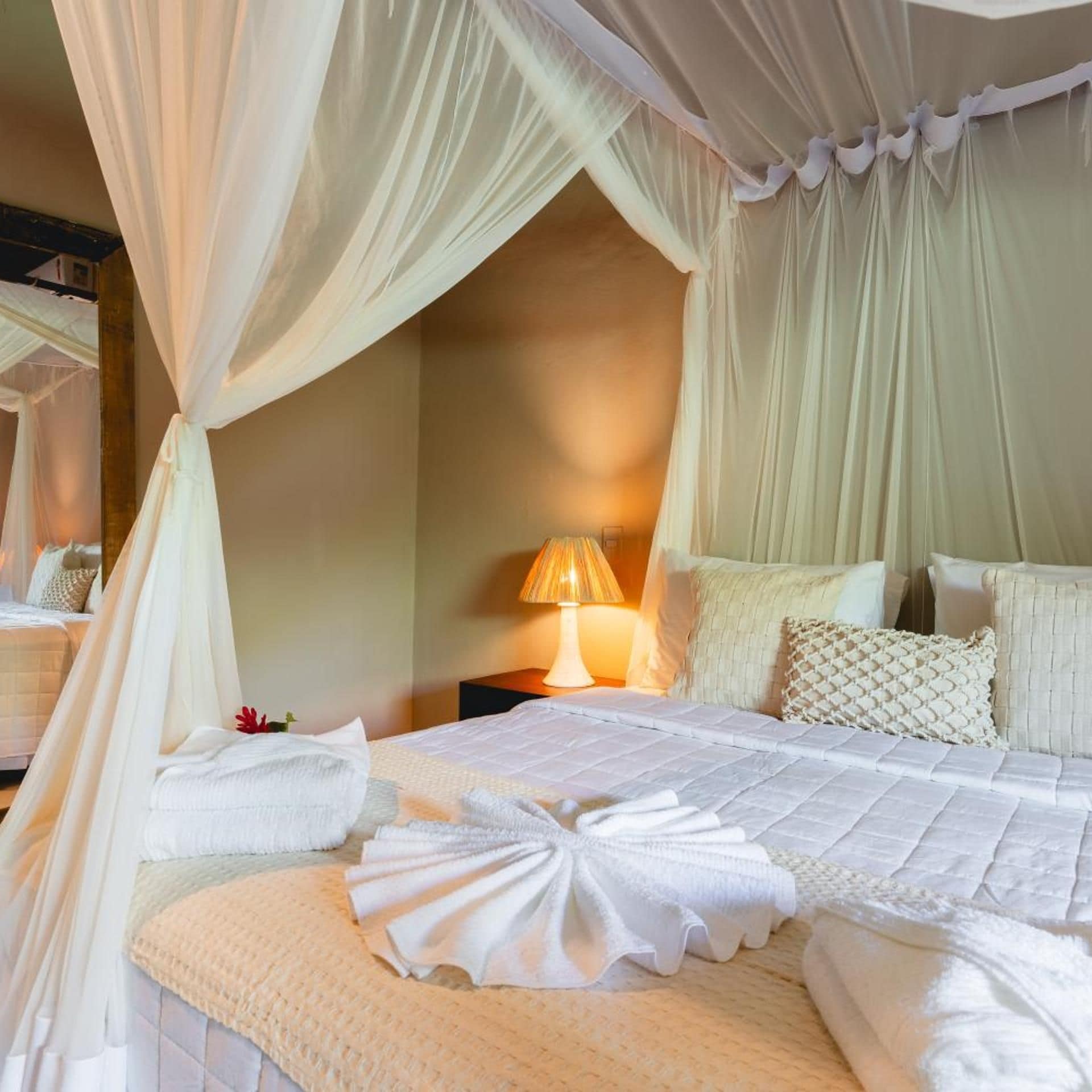 A hotel room with a bed, a nightstand, and a lamp.