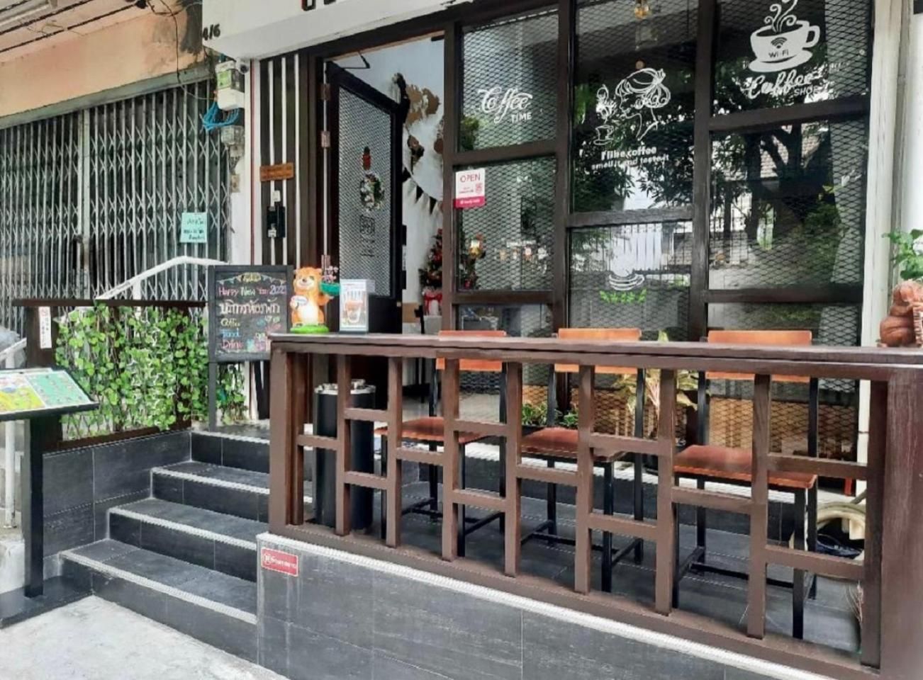 A café with outdoor seating, a staircase leading up to the entrance, and decorative elements on the windows.