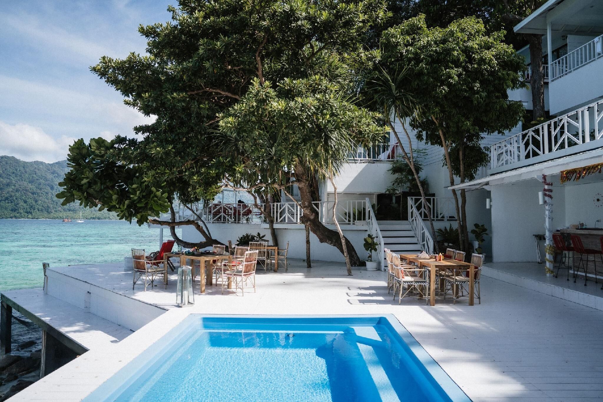 A poolside area with outdoor seating, a staircase, and a view of the sea.