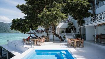 A poolside area with outdoor seating, a staircase, and a view of the sea.