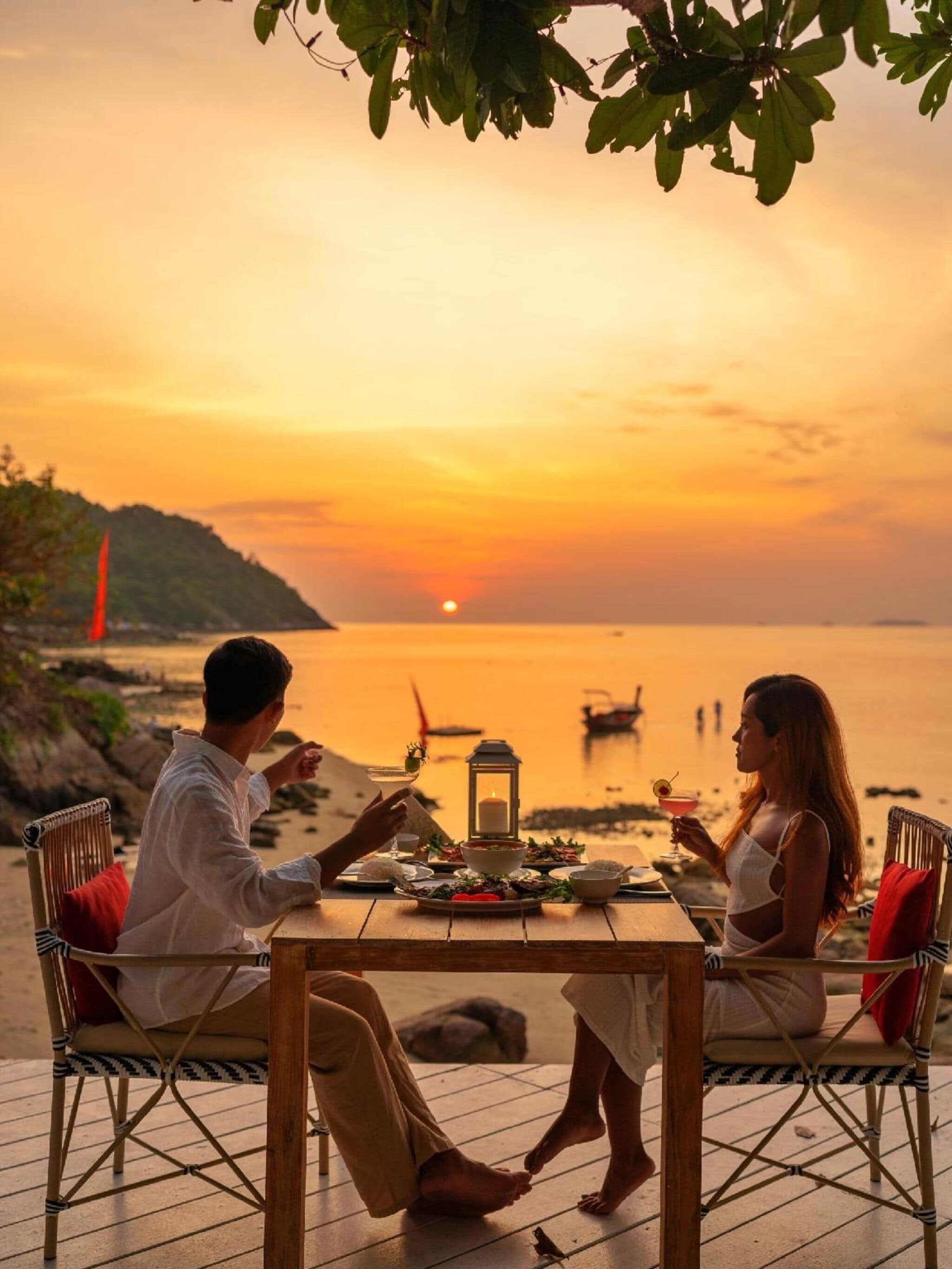 A sunset view with a table set for two, overlooking a body of water.
