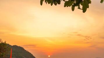 A sunset view with a table set for two, overlooking a body of water.
