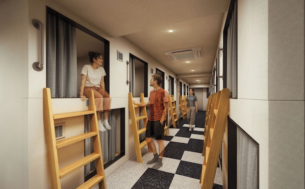 A corridor with bunk beds and wooden ladders, indicating a dormitory-style accommodation.