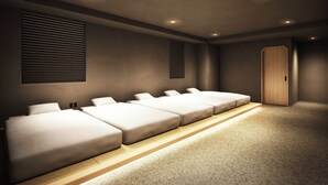 A hotel room with a row of beds, a wooden wardrobe, and a carpeted floor. - GRAND HOSTEL LDK Hiroshima (Hiroshima)