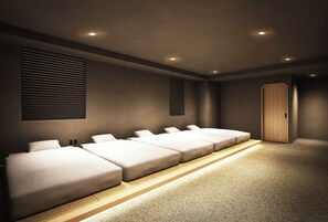 Ein Hotelzimmer mit mehreren Betten, einem Holzschrank und einem Teppichboden.