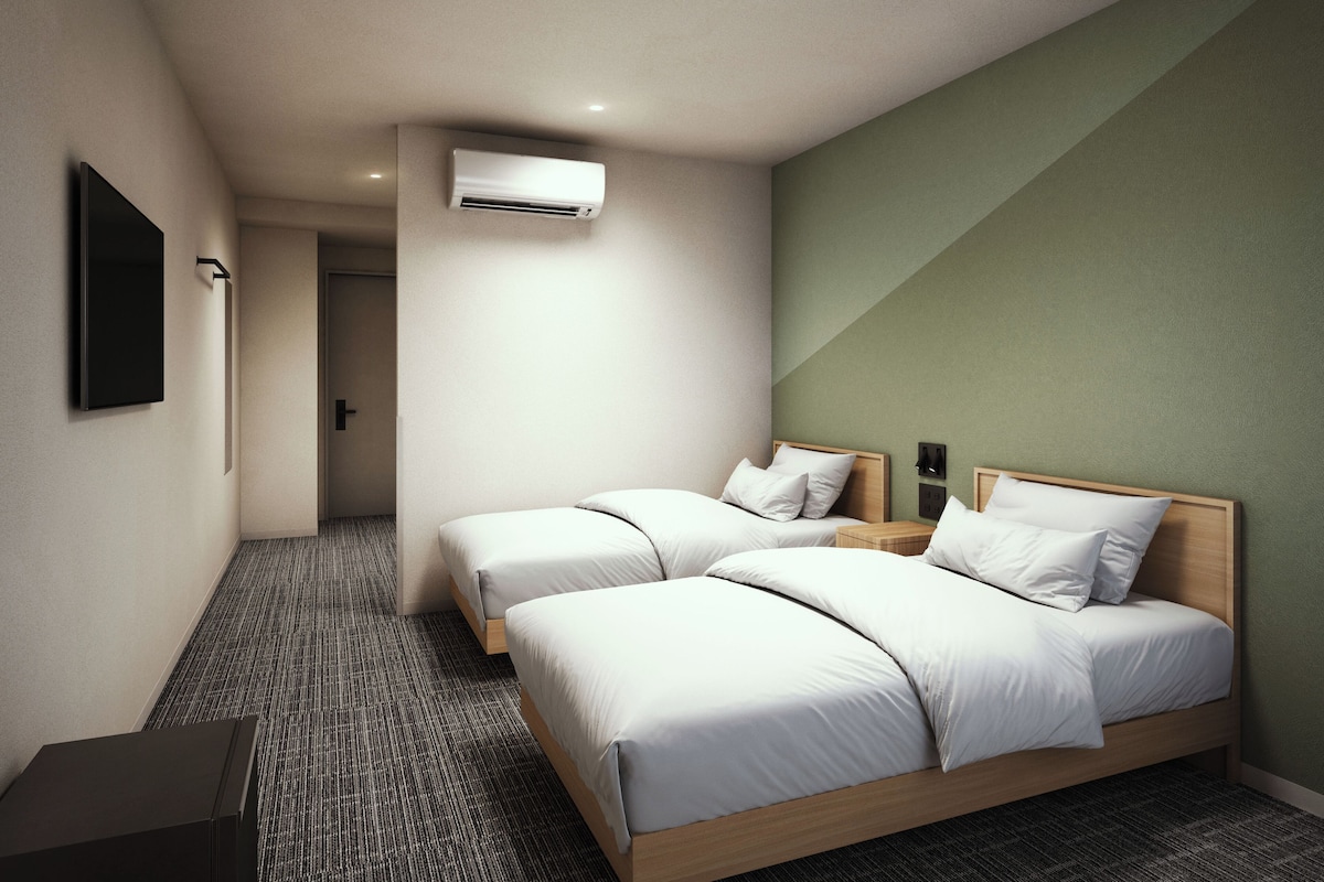 Ein Hotelzimmer mit zwei Betten, einem Flachbildfernseher, einer Klimaanlage und einem Teppichboden.
