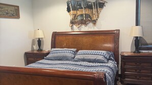 A bedroom with a wooden bed, a ceiling fan, a wall tapestry, and a nightstand with a lamp. - Kara Creek Ranch - 2 Bed/2 Bath - Cabin 11 (Sundance)