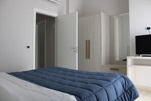 Un dormitorio con cama, armario, espejo y televisor.