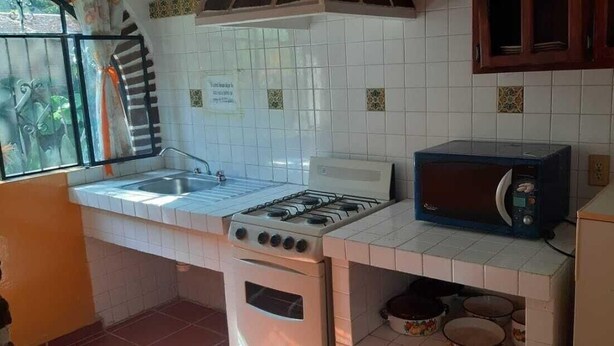 A kitchen with a gas stove, a microwave, and a sink. - Capital O Posada Del Pescador Jocotepec (Coatzacoalcos)