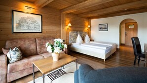 Ein Zimmer einer Holzhütte mit einem Bett, einer Couch, einem Tisch und einem Stuhl.