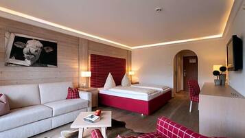 Ein modernes Hotelzimmer mit einer Couch, einem Bett, einem kleinen Tisch und einer roten Akzentwand.