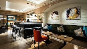 Eine moderne Bar mit Hockern, einer Theke und einer Sitzecke mit einer Couch und Tischen.