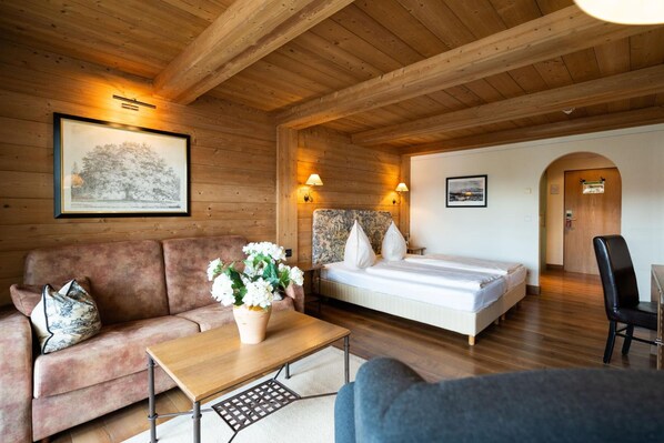 A wooden cabin room with a bed, a sofa, a table, and a chair. - Hotel Gasthof Alte Post Holzkirchen (Holzkirchen)