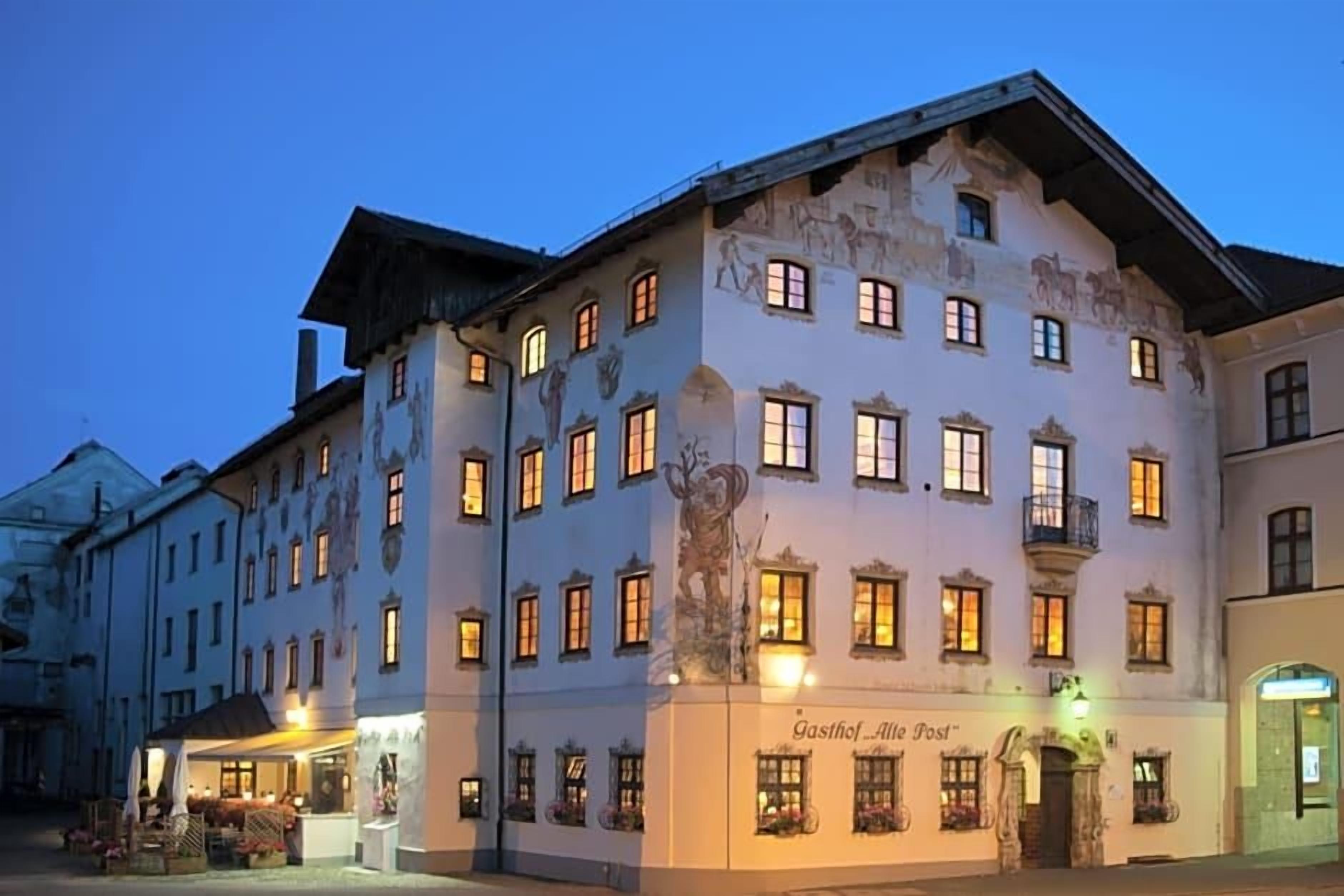 Ein historisches Gebäude mit zahlreichen Fenstern, einem zentralen Eingang und einem Schild mit der Aufschrift 'Gasthof Alte Post'.