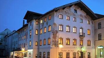 Ein historisches Gebäude mit zahlreichen Fenstern, einem zentralen Eingang und einem Schild mit der Aufschrift 'Gasthof Alte Post'.