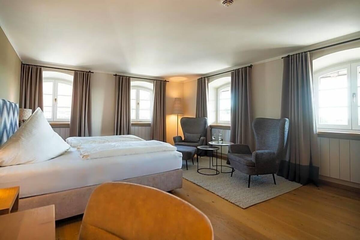Una habitación de hotel con cama, escritorio, silla y lámpara.