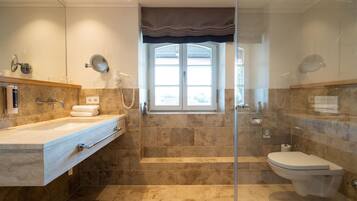 Ein modernes Badezimmer mit Duschkabine aus Glas, einem großen Fenster und einer separaten Toilette.